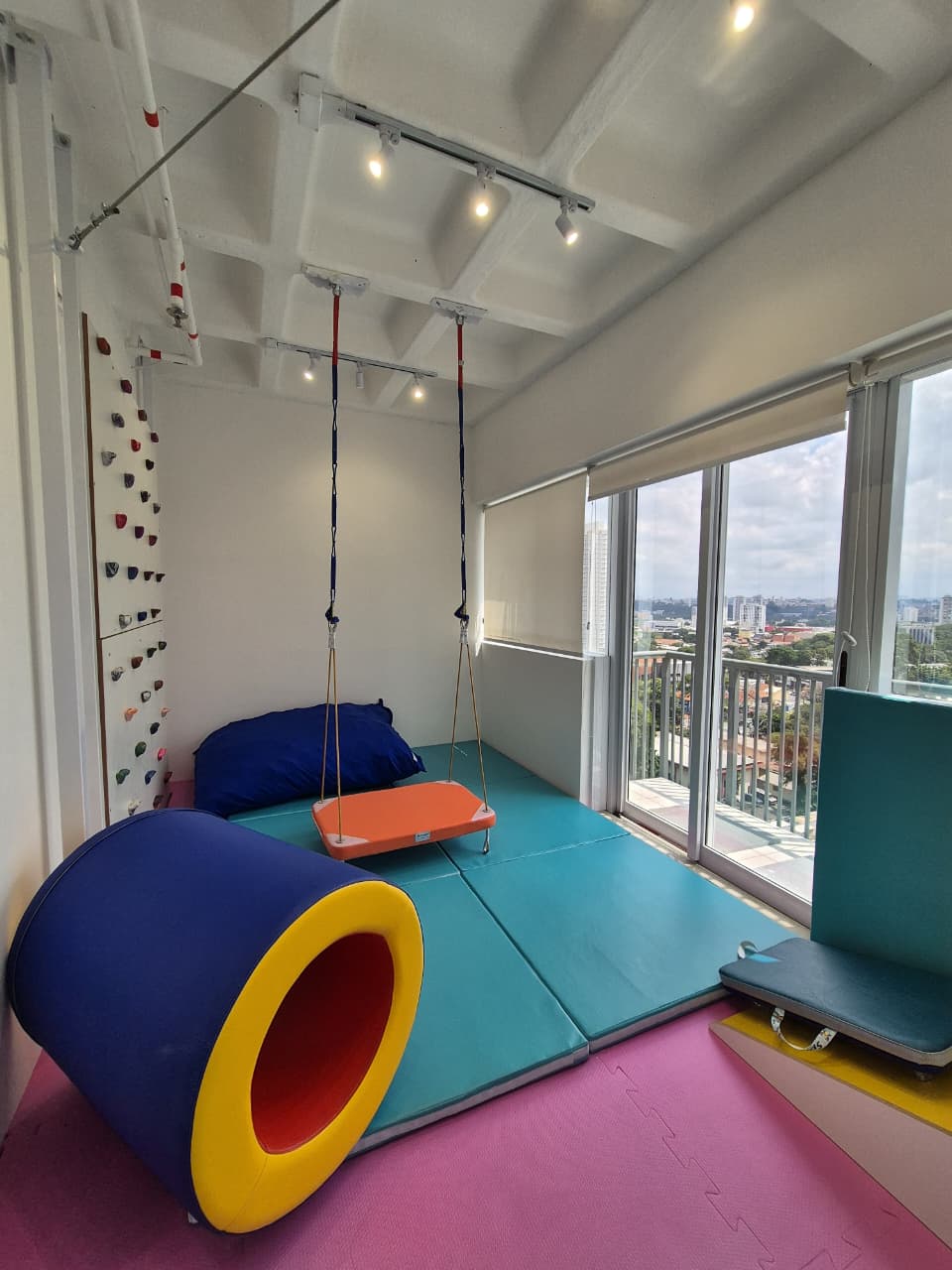 Sala de terapia com balanço e equipamentos sensoriais